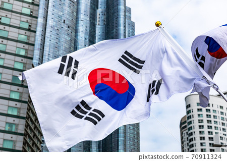 The Taegeuk flag fluttering vigorously against the backdrop of a commercial building The Taegeuk flag fluttering vigorously against the backdrop of a commercial building 70911324