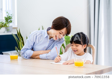 Parents and children doing homework in the living room. 70911358