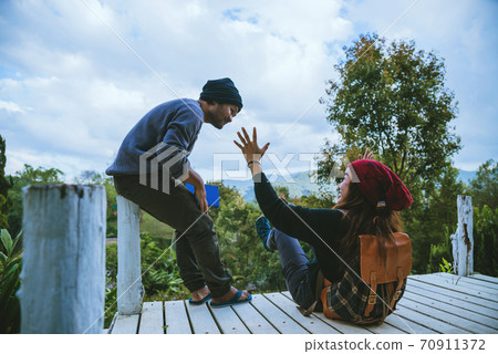 couple lover natural travel on the mountain, sitting relax reading books in the midst of nature on the white wooden bridge. couple lover natural travel on the mountain, sitting relax reading books in the midst of nature on the white wooden bridge. 70911372