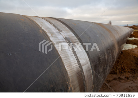a weld on an oil pipeline. View of the pipeline being assembled in the field. Cloudy day, autumn 70911659