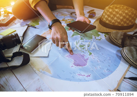 Tourist planning vacation with the help of world map Overhead view of Side view for travelers. Travel concept background, Young woman pointing to the map Australian. Tourist planning vacation with the help of world map Overhead view of Side view for travelers. Travel concept background, Young woman pointing to the map Australian. 70911894