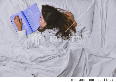 Young Woman Sleeping In Bed. Top view of young woman lying down sleeping well in bed. The girl who read the book in bed and Sleeping. sleeping relax Young Woman Sleeping In Bed. Top view of young woman lying down sleeping well in bed. The girl who read the book in bed and Sleeping. sleeping relax 70911895