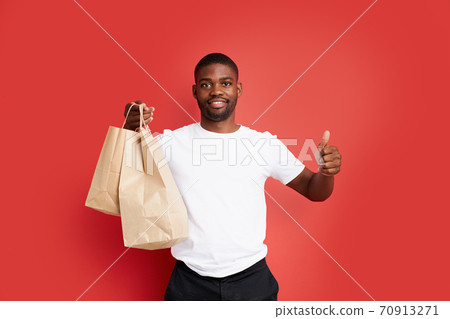 portrait of satisfied courier male with delivery food in paper bags portrait of satisfied courier male with delivery food in paper bags 70913271