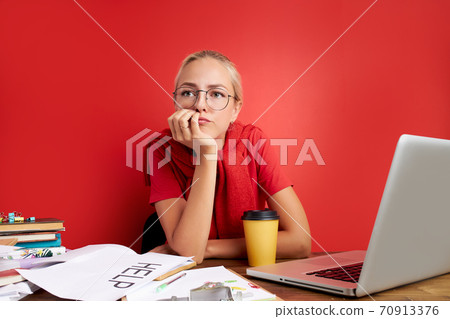 portrait of confident caucasian blonde female sitting at office desk with laptop and papers portrait of confident caucasian blonde female sitting at office desk with laptop and papers 70913376