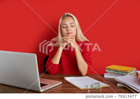 portrait of confident caucasian blonde female sitting at office desk with laptop and papers portrait of confident caucasian blonde female sitting at office desk with laptop and papers 70913477