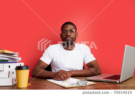 overworked unhappy and frustrated young african man in stress sitting at office desk 70914019