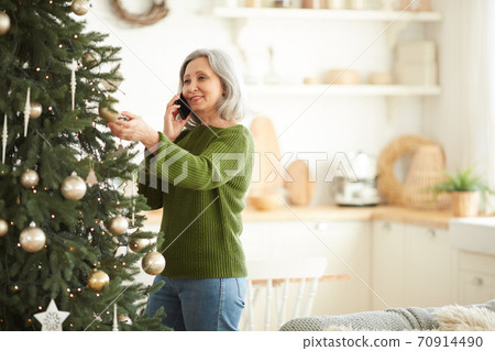 Woman decorating Christmas tree at home 70914490