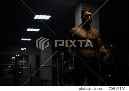 Strong male bodybuilder doing exercises with dumbbells 70916101