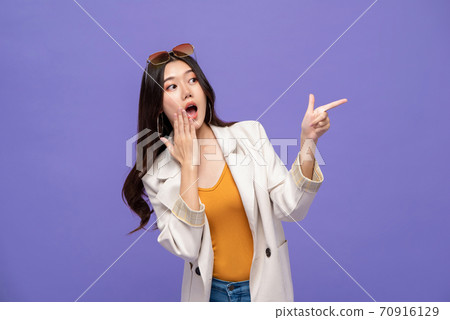 Shocked pretty Asian woman pointing hands to empty space aside  70916129