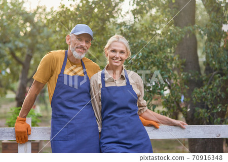 Middle aged caucasian partners standing in garden Middle aged caucasian partners standing in garden 70916348