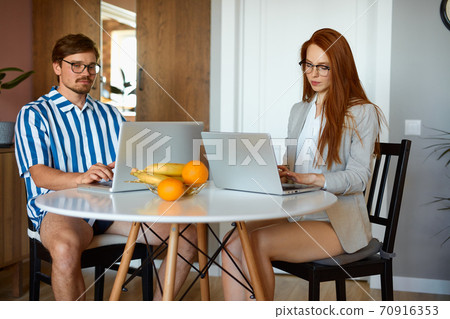 married couple work on laptop at home 70916353