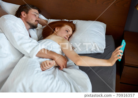 woman take selfie while husband is sleeping woman take selfie while husband is sleeping 70916357