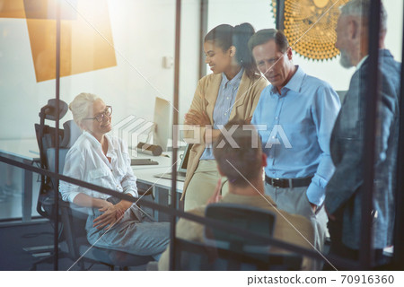 Office life. Group of cheerful multi ethnic business people talking and smiling while working together in the modern office, having a meeting in boardroom Office life. Group of cheerful multi ethnic business people talking and smiling while working together in the modern office, having a meeting in boardroom 70916360