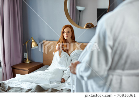 confused young pretty redhaired lady looking at naked man, disappointed about small size confused young pretty redhaired lady looking at naked man, disappointed about small size 70916361