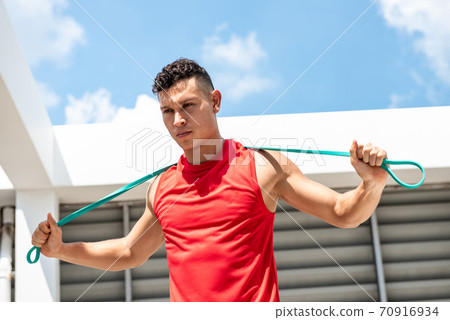 Handsome athletic man stretching with resistance band outdoors  70916934