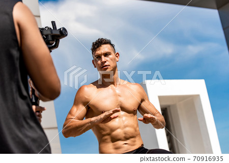 Handsome muscular man fitness influencer recording exercise video clip ourdoors 70916935