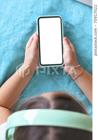 A teenager with headphones is holding a phone. White screen free for text. The concept of the use of A teenager with headphones is holding a phone. White screen free for text. The concept of the use of 70917022