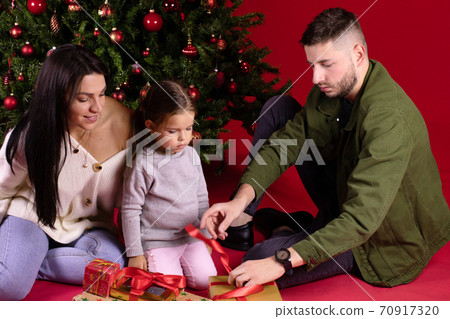 Young father helping his daughter to open Christmas gifts. Men's work concept Young father helping his daughter to open Christmas gifts. Men's work concept 70917320
