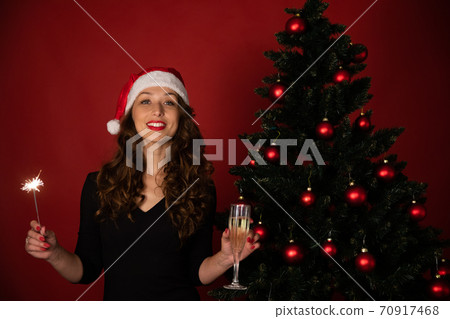 Beautiful brunette girl in Santa Claus hat takes Christmas greetings online 70917468
