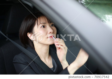 Woman applying makeup in the car Woman applying makeup in the car 70917542