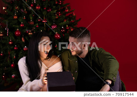 Young excited woman with husband looking at Christmas magic gift miracle concept Young excited woman with husband looking at Christmas magic gift miracle concept 70917544