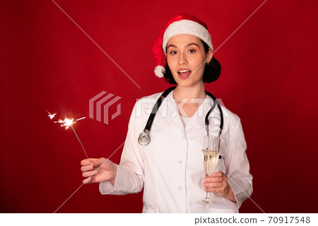 attractive sexy female doctor looking at camera glass of champagne and sparklers attractive sexy female doctor looking at camera glass of champagne and sparklers 70917548