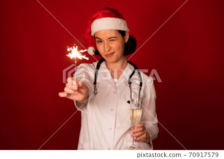 pretty sexy female doctor wink at camera with champagne and Burning sparklers 70917579