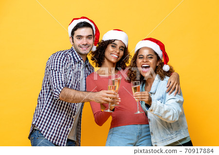 Three excited diverse friends celebrating Christmas drinking champagne together Three excited diverse friends celebrating Christmas drinking champagne together 70917884