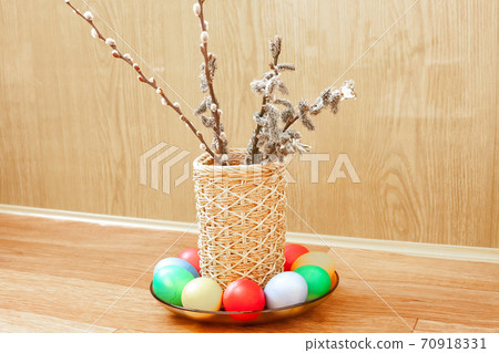 Wicker vase with willow branch and colored eggs for Easter 70918331