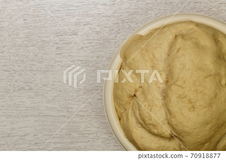 Fragment of the bowl with a raised fermented yeast dough. On the table. 70918877