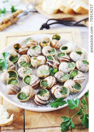Escargots, traditional French cuisine: snails sauce Burgundy and baguette on light background Escargots, traditional French cuisine: snails sauce Burgundy and baguette on light background 70919257