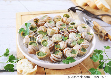 Escargots, traditional French cuisine: snails sauce Burgundy and baguette on light background Escargots, traditional French cuisine: snails sauce Burgundy and baguette on light background 70919258