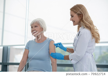 Pretty young nurse making vaccination to an elderly woman Pretty young nurse making vaccination to an elderly woman 70922714