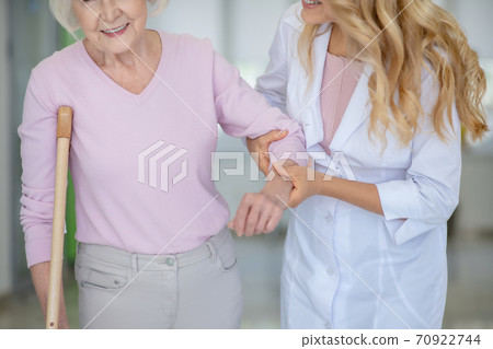 Nurse supporting an elderly woman in a pink shirt Nurse supporting an elderly woman in a pink shirt 70922744
