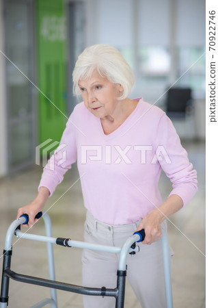 Elderly woman walking with a rolling-walker Elderly woman walking with a rolling-walker 70922746