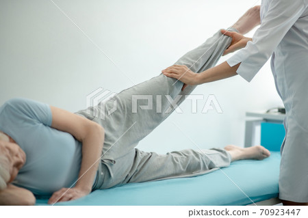 Doctor examining the legs joints of an elderly woman 70923447