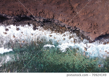 Aerial top view of waves splashing on rocky volcanic coastline. High quality photo. 70924149