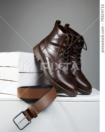 Male brown boots and belt on white wooden box Male brown boots and belt on white wooden box 70924718