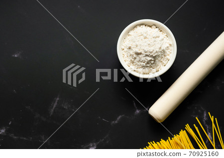 Bowl of flour on dark backdrop. 70925160