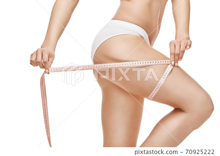 Slim tanned woman's body isolated on white background - waist measurement 70925222