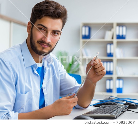 IT technician looking at IT equipment IT technician looking at IT equipment 70925307