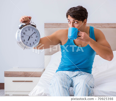 Young man waking up in bed 70925398