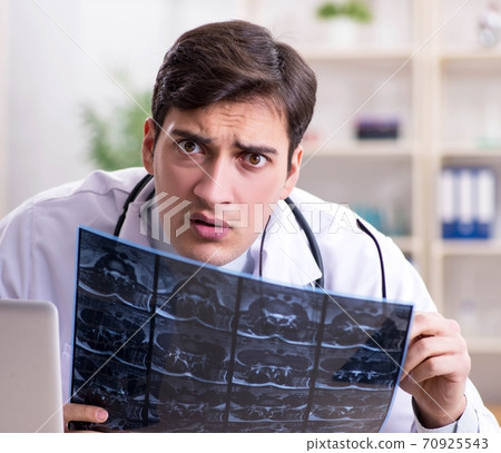 Young doctor looking at x-ray images in clinic 70925543