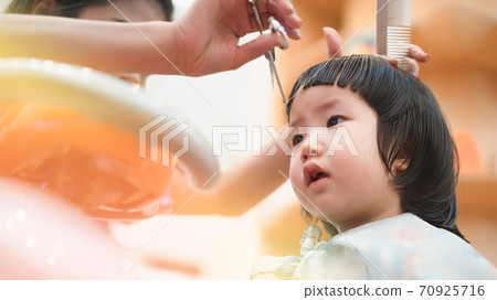 Home haircut of 2 year old Asian toddler by mother in the household during Covid-19 coronavirus pandemic, self-quarantine, social distancing, DIY, mother daughter relationship, homeschool, family bond 70925716