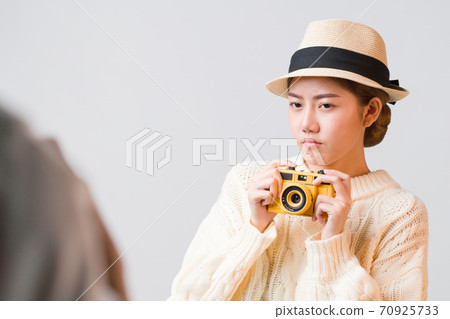 Cute young Asian tourist woman holding camera in her hand with thinking expression on her face isolated in grey background with copy space, negative expression, Explore and think before shoot concept. 70925733
