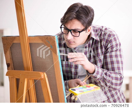 Young male artist drawing pictures in bright studio 70926478