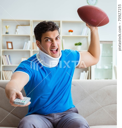 Man with neck injury watching american football at home 70927255