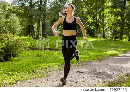 Young woman is runnning in public park. Young woman is runnning in public park. 70927433