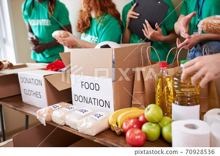 diverse volunteers collecting food and clothes donations in warehouse diverse volunteers collecting food and clothes donations in warehouse 70928536