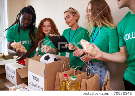 happy young volunteers donating clothes and food for charity, indoors 70928548